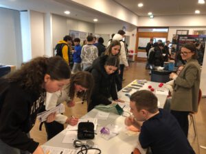 Schüler*innen stehen an einem Stand und informieren sich über verschiedene Berufsfelder